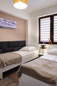 - une chambre avec 2 lits et une fenêtre dans l'établissement Apartament SŁOWIK, à Krynica-Zdrój