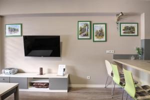 uma sala de estar com uma televisão e uma mesa e cadeiras em Apartament SŁOWIK em Krynica-Zdrój