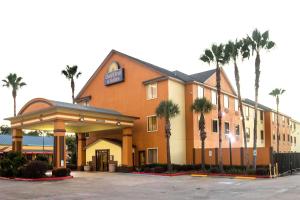 ein Hotel mit Palmen auf einem Parkplatz in der Unterkunft Days Inn & Suites by Wyndham Houston North/Aldine in Houston