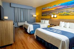 a hotel room with two beds and a flat screen tv at Days Inn & Suites by Wyndham Houston North/Aldine in Houston