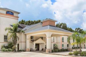 un gran edificio blanco con palmeras delante en Howard Johnson by Wyndham Houma, en Houma