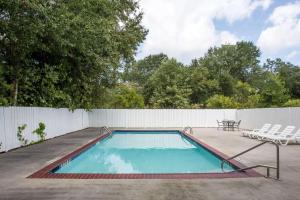 einen Pool mit Stühlen und einem Zaun in der Unterkunft Howard Johnson by Wyndham Houma in Houma