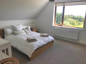 a bedroom with a large bed with a window at Tinnaberna Lodge Kilmuckridge in Kilmuckridge