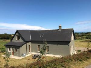 a gray house with a black roof on a field at Tinnaberna Lodge Kilmuckridge in Kilmuckridge