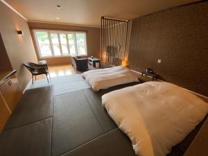 a bedroom with two beds and a desk and a chair at Auberge Mermaid in Fujikawaguchiko