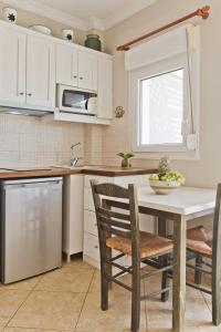 a kitchen with white cabinets and a table and chairs at Kalimera Karpathos Exclusive Villas in Afiartis