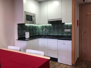 a kitchen with white cabinets and a red counter top at Pizarro55 By Vigovacaciones in Vigo +7 photos