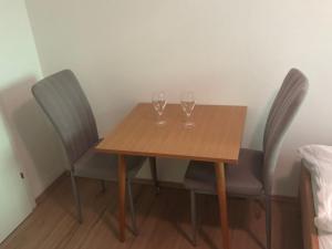dois copos de vinho numa mesa de madeira com duas cadeiras em Schmitten Haus em Zell am See