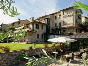 eine Terrasse mit Tischen und einem Sonnenschirm vor einem Gebäude in der Unterkunft Hotel La Terrazza RESTAURANT & SPA in Assisi