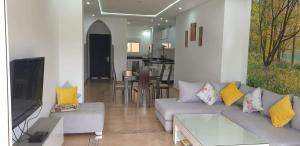 uma sala de estar com um sofá cinzento e almofadas amarelas em Appart marina saidia ap8 em Saïdia