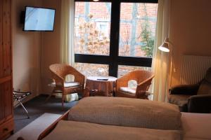 a room with a bed and chairs and a window at Landhotel Belitz Garni in Küsten