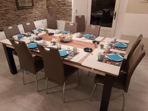 una mesa de comedor con sillas y una mesa de madera con comida. en La Fermette Blanche, en Nadrin