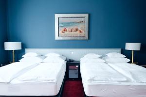 two beds in a hotel room with blue walls at Hotel Bamberger Hof Bellevue in Bamberg