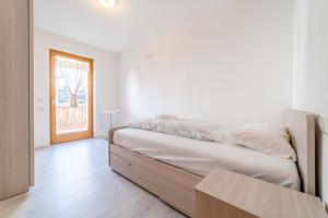 biała sypialnia z łóżkiem i drewnianą podłogą w obiekcie Olivia Home w mieście Caprile