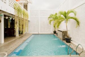 a swimming pool with a palm tree in a building at Otu Hostel By Ostic in Yogyakarta