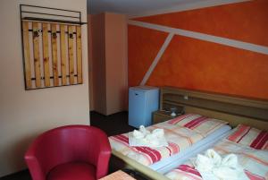 a bedroom with a bed and a red chair at Pension Adolfshaide in Wurzbach
