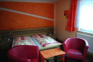 a small bedroom with a bed and two chairs at Pension Adolfshaide in Wurzbach