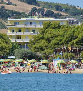 un groupe de personnes sur une plage avec un hôtel dans l'établissement Residence Costa, à Alba Adriatica