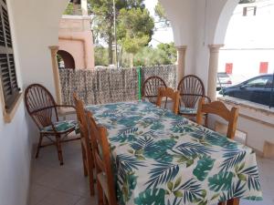una mesa y sillas en el porche de una casa en VILLA FLOR, en Cala Figuera