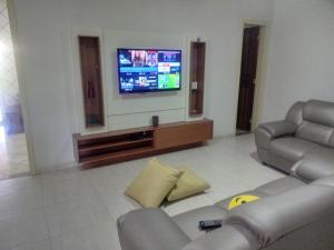 a living room with a couch and a tv at Casa de Temporada com Piscina in Serra