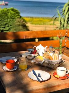 a wooden table with a breakfast of food and drinks at Hotel Costanera in Villarrica