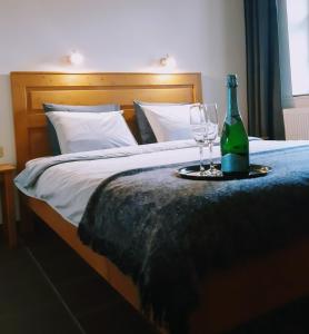 uma cama com uma garrafa de vinho e dois copos em Tisza Lodge B&B - Panzió em Tiszaderzs