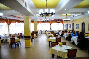 a restaurant with tables and chairs and people sitting at them at Pensiunea Bachus in Piatra Neamţ