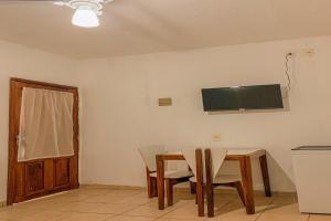 a dining room with a table and chairs and a television on the wall at Pousada Migo in Porto Seguro