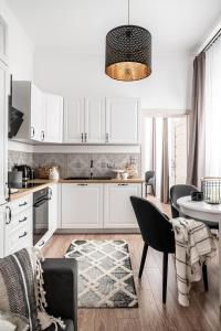 a kitchen with white cabinets and a table with chairs at Apartament Biała Perła in Czarny Dunajec