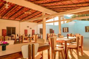 a dining room with tables and chairs and a large window at Pousada Migo in Porto Seguro