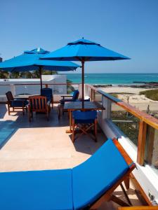 um deque com mesas e guarda-sóis na praia em Drake Inn em Puerto Villamil