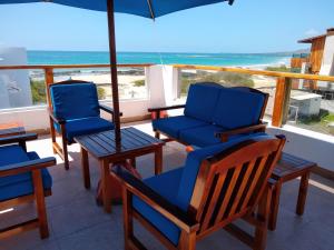 2 stoelen en een parasol op een balkon met uitzicht op de oceaan bij Drake Inn in Puerto Villamil