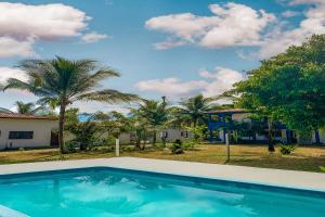 a swimming pool in front of a house with palm trees at Pousada Migo in Porto Seguro