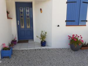 eine blaue Tür in einem weißen Gebäude mit Topfpflanzen in der Unterkunft studio lumineux dans la coulée verte à Saint gilles croix de vie in Saint-Gilles-Croix-de-Vie
