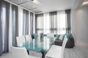 een eetkamer met een glazen tafel en witte stoelen bij Mayra Seafront Luxury Apartment (BREAKBOOKING-CY) in Limassol