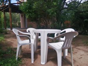 four white chairs around a white table in a yard at Casa La Toma in Capilla del Monte +14 photos