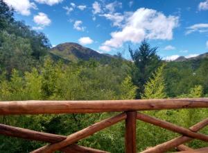 a view of the mountains from a wooden railing at Casa La Toma in Capilla del Monte