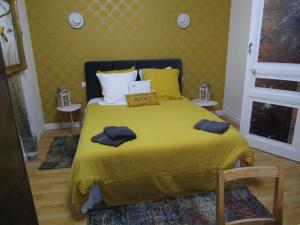 a bedroom with a yellow bed with two towels on it at Chambre d'hôtes Au Nid du Thil in Beauvais