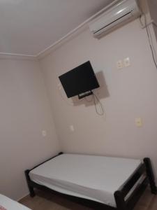 Habitación pequeña con cama y TV de pantalla plana. en Pousada Casebre, en Pirenópolis