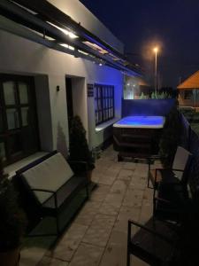 - un patio la nuit avec une baignoire et des chaises dans l'établissement Városi Idill, à Veszprém