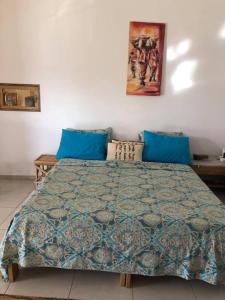a bedroom with a large bed with blue pillows at La Maison Aziz - Somone - Sénégal in Somone