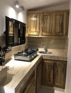 a kitchen with wooden cabinets and a stove and a sink at La Maison Aziz - Somone - Sénégal in Somone
