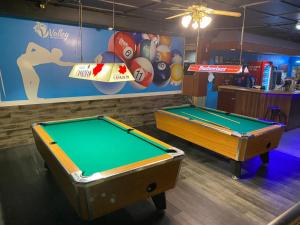 duas mesas de bilhar numa sala de jogos com uma placa em Valley Motor Lodge em Minnedosa