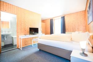 Habitación de hotel con cama y baño en Hotel Landhaus Adler, en Frutigen