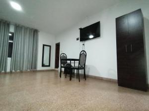 Zimmer mit einem Tisch und Stühlen sowie einem Flachbild-TV in der Unterkunft Suite Trujillo in Trujillo
