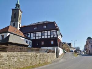 a building with a clock tower next to a street at Hotel RON in Mikulášovice