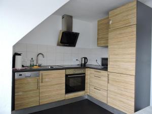 a kitchen with wooden cabinets and a sink at Ferienwohnungen Fabry in Saarbrücken