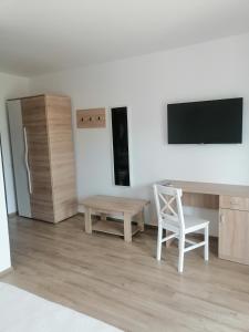 a living room with a table and a chair and a tv at AristoCat Hotels Rasnov in Râşnov