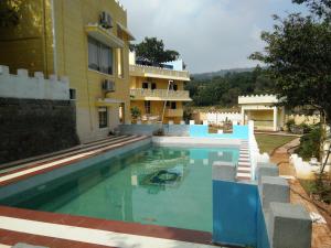 a swimming pool in front of a building at Hillfort Hotels & Resorts Yelagiri in Yelagiri