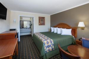 a hotel room with a large bed and a table at Travelodge by Wyndham Orangeburg in Orangeburg